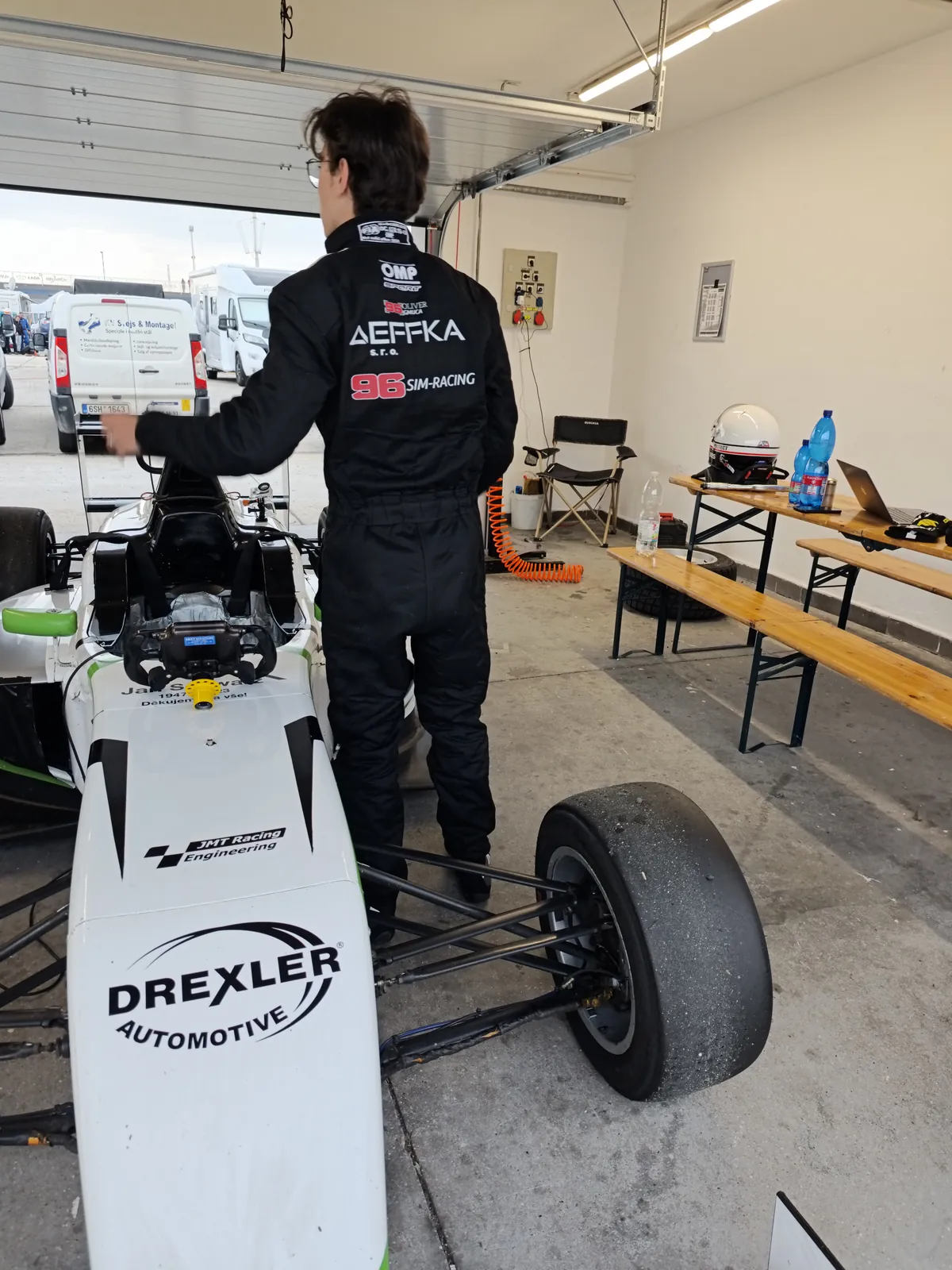 Oliver in race suit next to his Formula 4 car in the garage